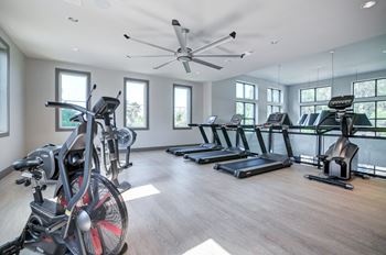 a gym with treadmills and weights and a ceiling fan at Century Town Center, Gainesville, FL, 32607